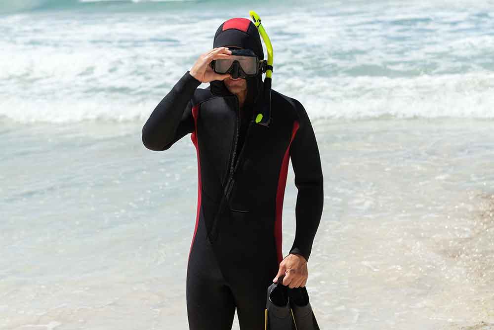 69874148_male-diver-with-fins-and-neoprene-suit-on-the-beach